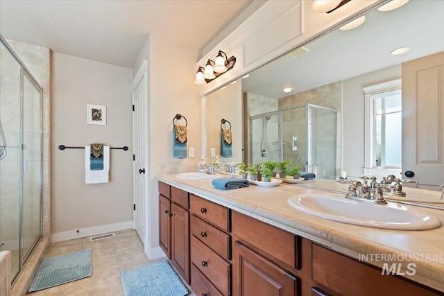 bathroom featuring a shower stall, double vanity, tile patterned flooring, and baseboards