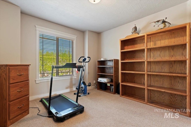workout area featuring carpet floors, a textured ceiling, and baseboards