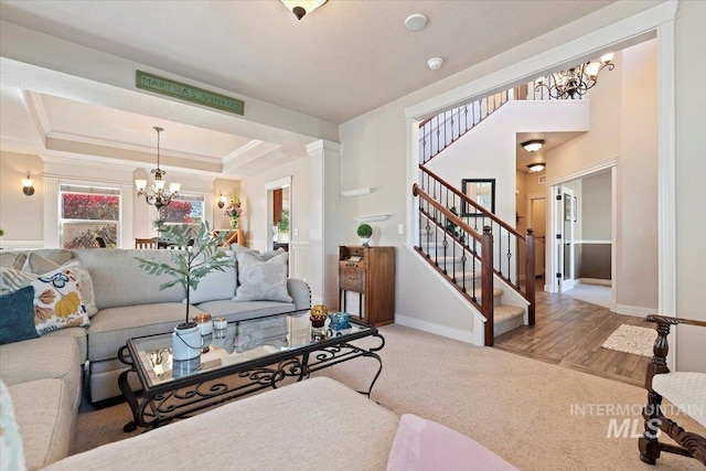 living room featuring a chandelier, stairway, baseboards, carpet floors, and a tray ceiling