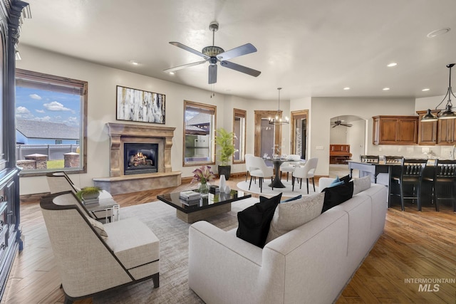 living area with recessed lighting, ceiling fan with notable chandelier, plenty of natural light, and a glass covered fireplace