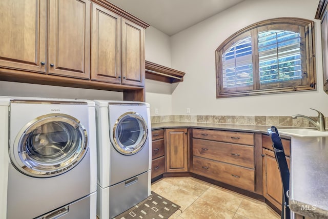 washroom with light tile patterned floors, washing machine and dryer, cabinet space, and a sink