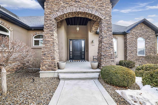 property entrance with stucco siding and stone siding