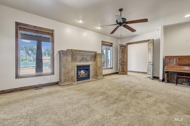 unfurnished living room featuring ceiling fan, a wealth of natural light, carpet, and a fireplace