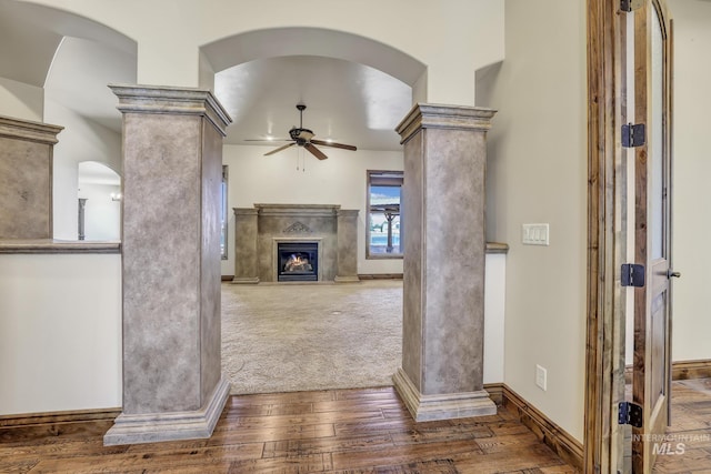 unfurnished living room with baseboards, decorative columns, hardwood / wood-style flooring, and a ceiling fan