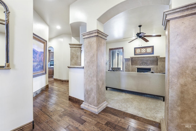 interior space with ornate columns, arched walkways, ceiling fan, and a fireplace
