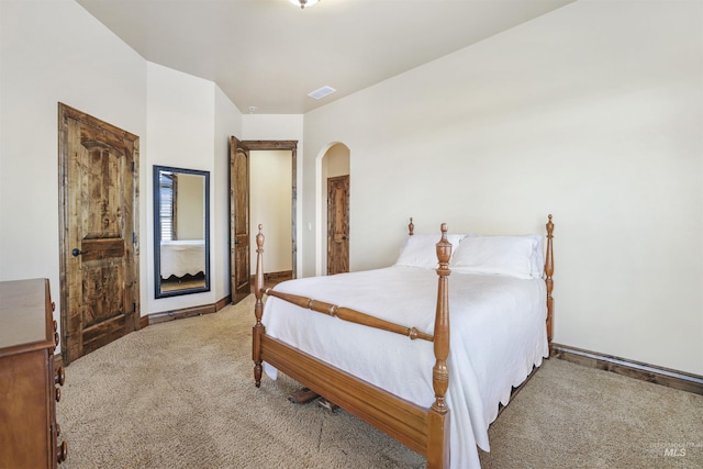 carpeted bedroom featuring arched walkways, visible vents, and baseboards