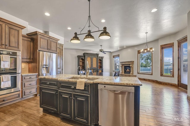 kitchen featuring pendant lighting, a sink, stainless steel appliances, an island with sink, and a ceiling fan
