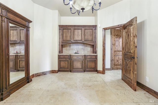 bar with an inviting chandelier, backsplash, and baseboards