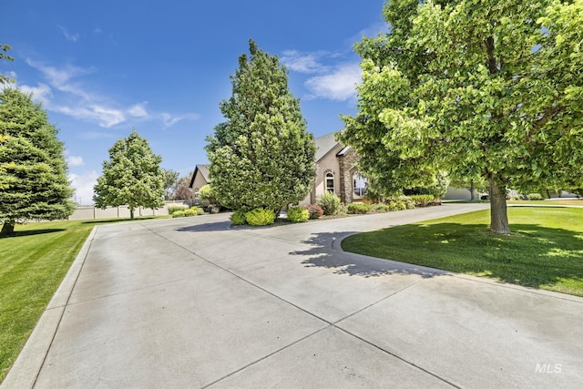 view of front of house with fence, curved driveway, and a front yard