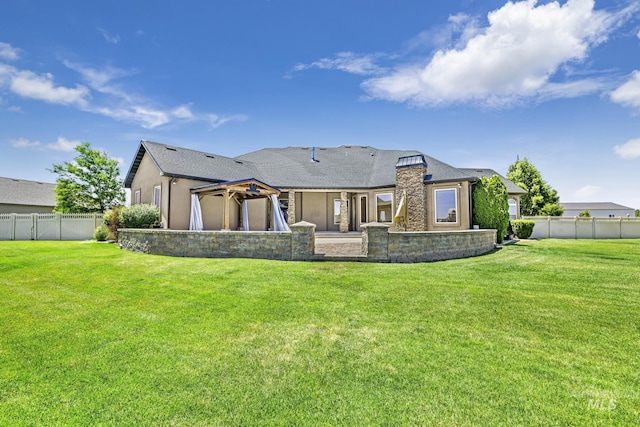 rear view of house with a lawn, a gazebo, and a fenced backyard
