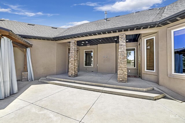 back of house featuring a shingled roof and stucco siding
