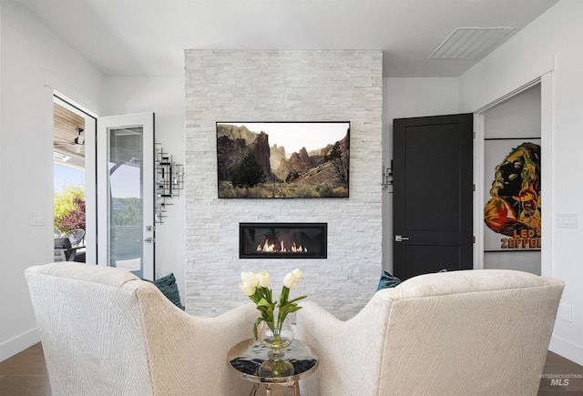 living room featuring dark hardwood / wood-style floors and a stone fireplace