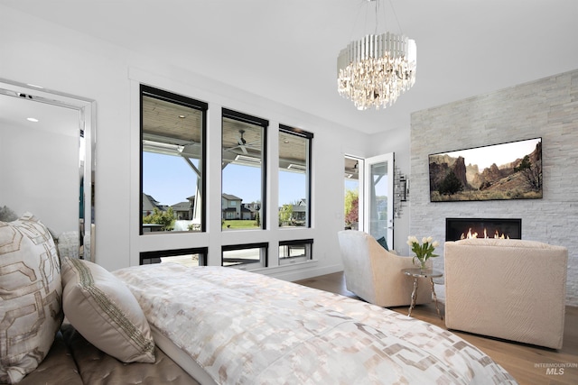 bedroom featuring a fireplace, an inviting chandelier, and light hardwood / wood-style flooring