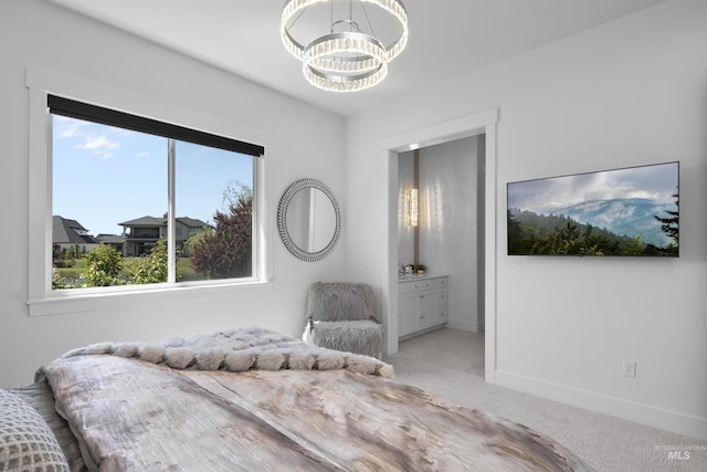 carpeted bedroom featuring ensuite bath and an inviting chandelier