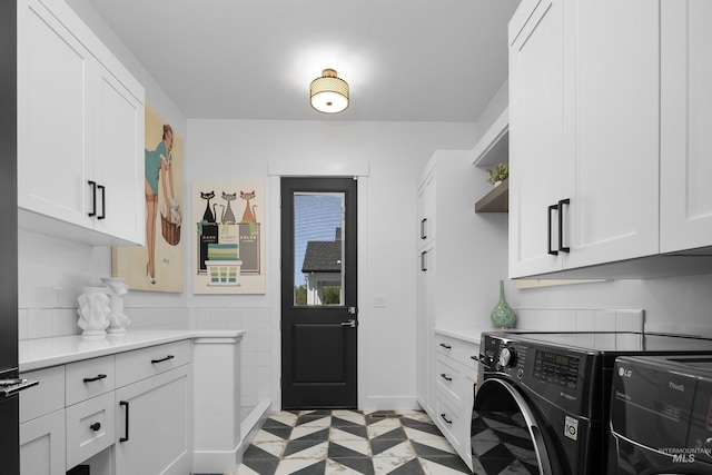 clothes washing area featuring cabinets and washing machine and clothes dryer