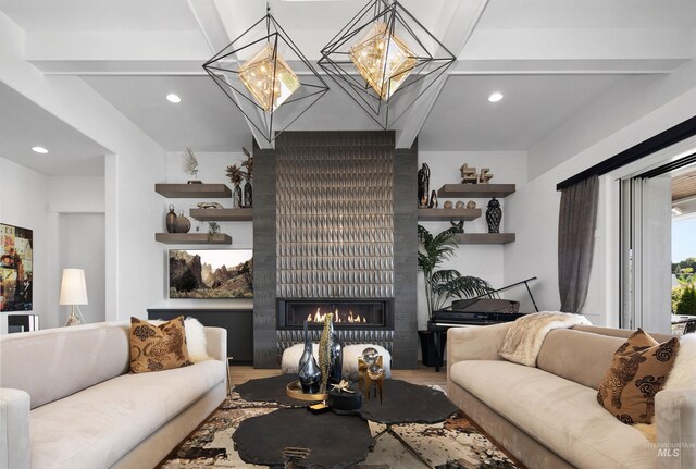 living room with beam ceiling, wood-type flooring, a fireplace, and an inviting chandelier