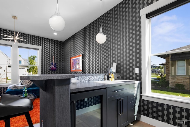 bar with decorative light fixtures, wine cooler, a wealth of natural light, and sink