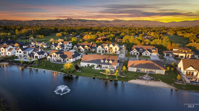 aerial view at dusk featuring a water and mountain view