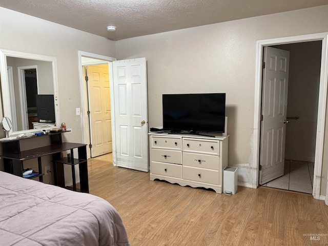 bedroom with light hardwood / wood-style floors and a textured ceiling