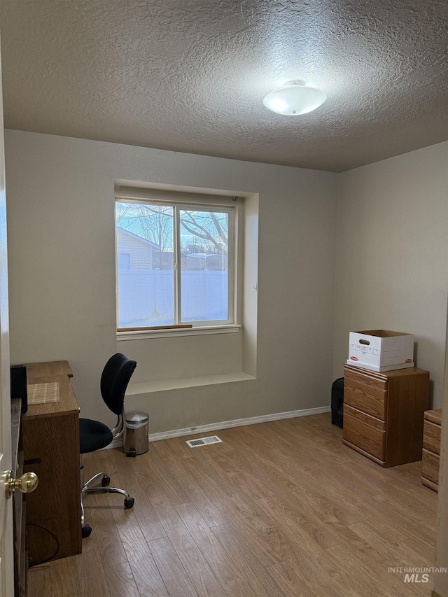 home office featuring light hardwood / wood-style floors and a textured ceiling