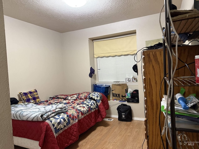 bedroom with light hardwood / wood-style flooring and a textured ceiling