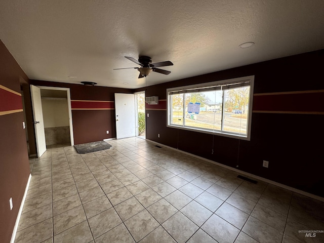 unfurnished bedroom featuring ceiling fan, a wall unit AC, a textured ceiling, a closet, and light tile patterned floors