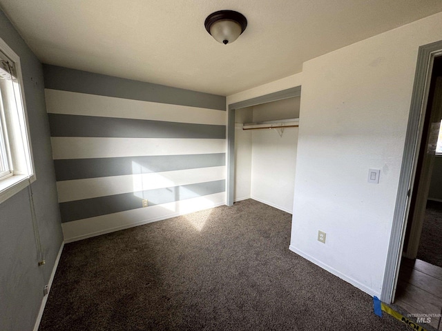 unfurnished bedroom featuring dark carpet and a closet