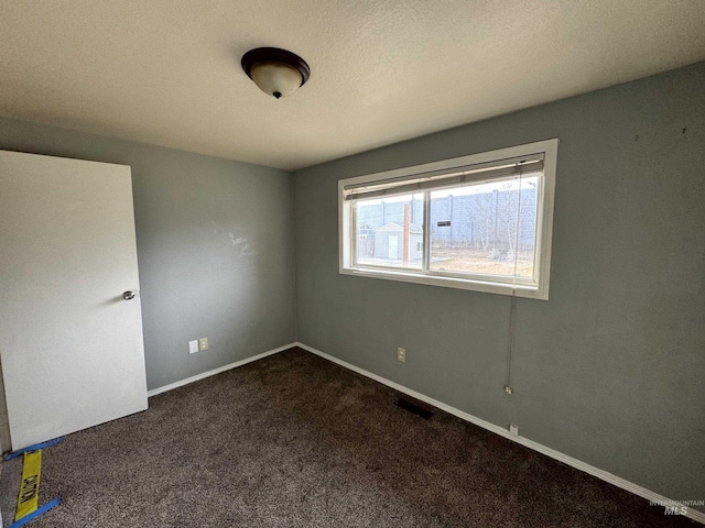 spare room featuring dark colored carpet