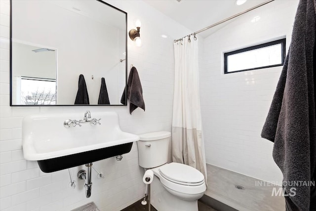 bathroom with tile walls, sink, toilet, and walk in shower