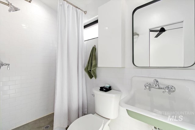 bathroom featuring sink, curtained shower, tile walls, and toilet