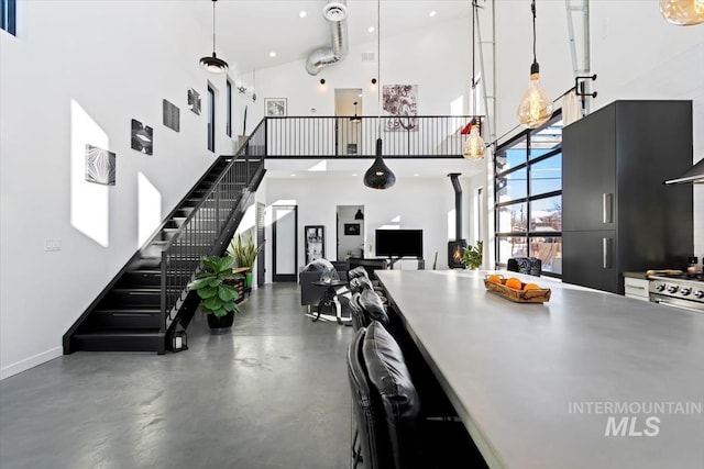 kitchen featuring a high ceiling, concrete floors, and decorative light fixtures