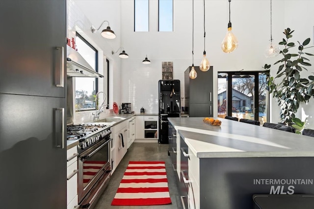 kitchen featuring sink, white cabinetry, premium appliances, a kitchen island, and pendant lighting