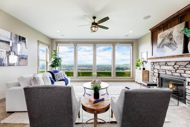 living room with ceiling fan and a stone fireplace