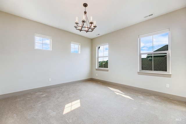 carpeted spare room featuring a notable chandelier