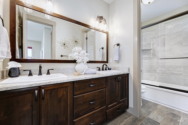 full bathroom with shower / bath combination with glass door, dual vanity, tile patterned flooring, and toilet