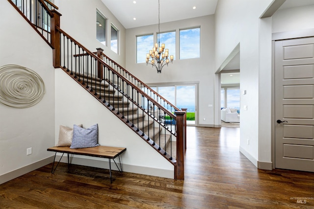 foyer entrance featuring hardwood / wood-style flooring, a chandelier, and a high ceiling