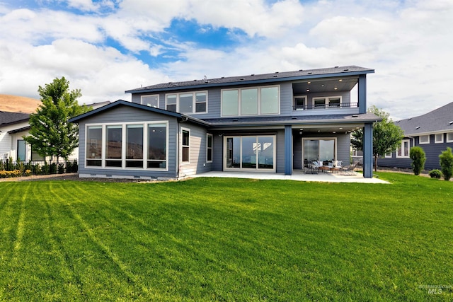 rear view of property featuring a patio area, a balcony, and a yard