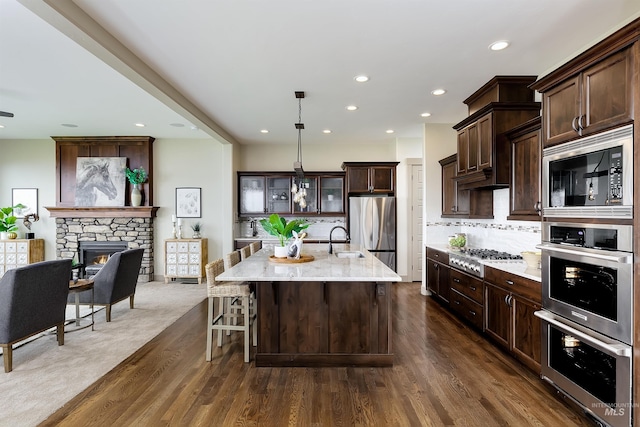 kitchen with tasteful backsplash, a fireplace, dark wood-type flooring, and stainless steel appliances