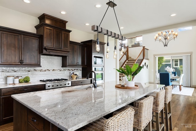 kitchen with sink, backsplash, light stone counters, and dark hardwood / wood-style floors