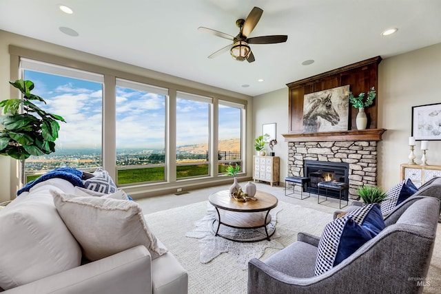 living room with ceiling fan, a fireplace, and light carpet