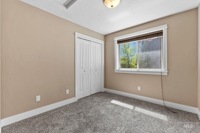 unfurnished bedroom with baseboards, carpet flooring, and a closet
