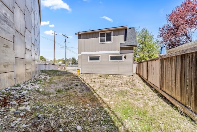 back of property with board and batten siding, roof with shingles, and a fenced backyard