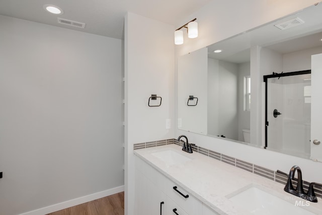 bathroom with vanity, hardwood / wood-style flooring, a shower with shower door, and toilet