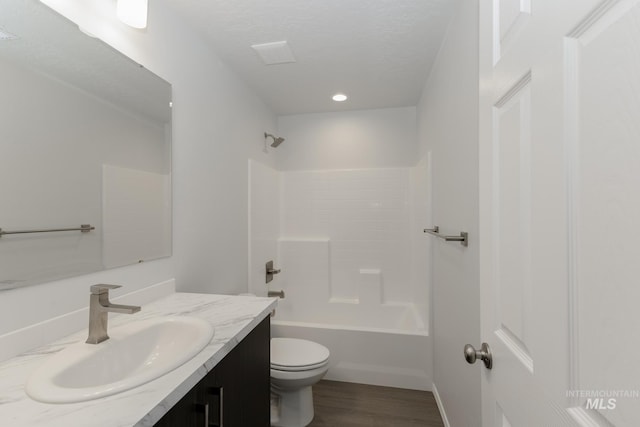 full bathroom with shower / bathing tub combination, vanity, wood-type flooring, a textured ceiling, and toilet