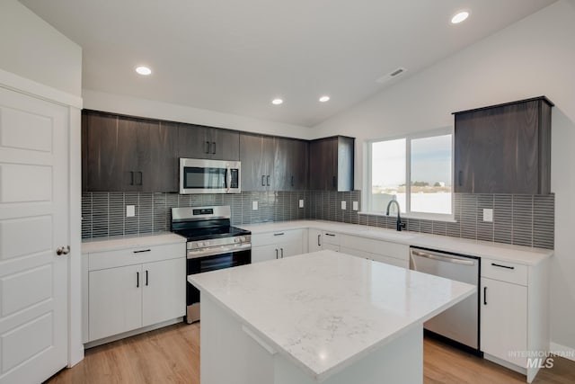 kitchen featuring appliances with stainless steel finishes, lofted ceiling, sink, a center island, and dark brown cabinets