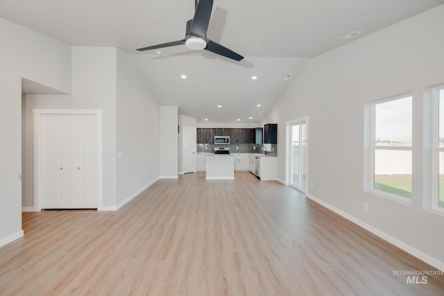 unfurnished living room with ceiling fan, plenty of natural light, high vaulted ceiling, and light hardwood / wood-style flooring