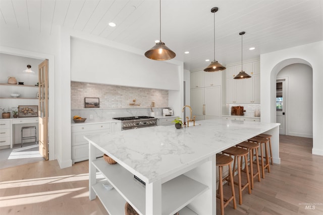 1734 S S Riparian Way, Eagle, ID 83616 - kitchen featuring open shelves, light wood finished floors, high end stainless steel range, tasteful backsplash, and arched walkways