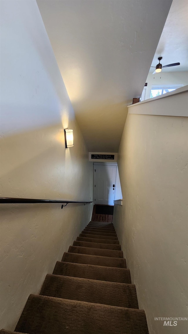 stairs featuring ceiling fan