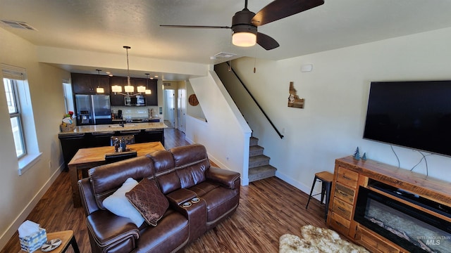 living room featuring ceiling fan with notable chandelier, dark hardwood / wood-style floors, and sink