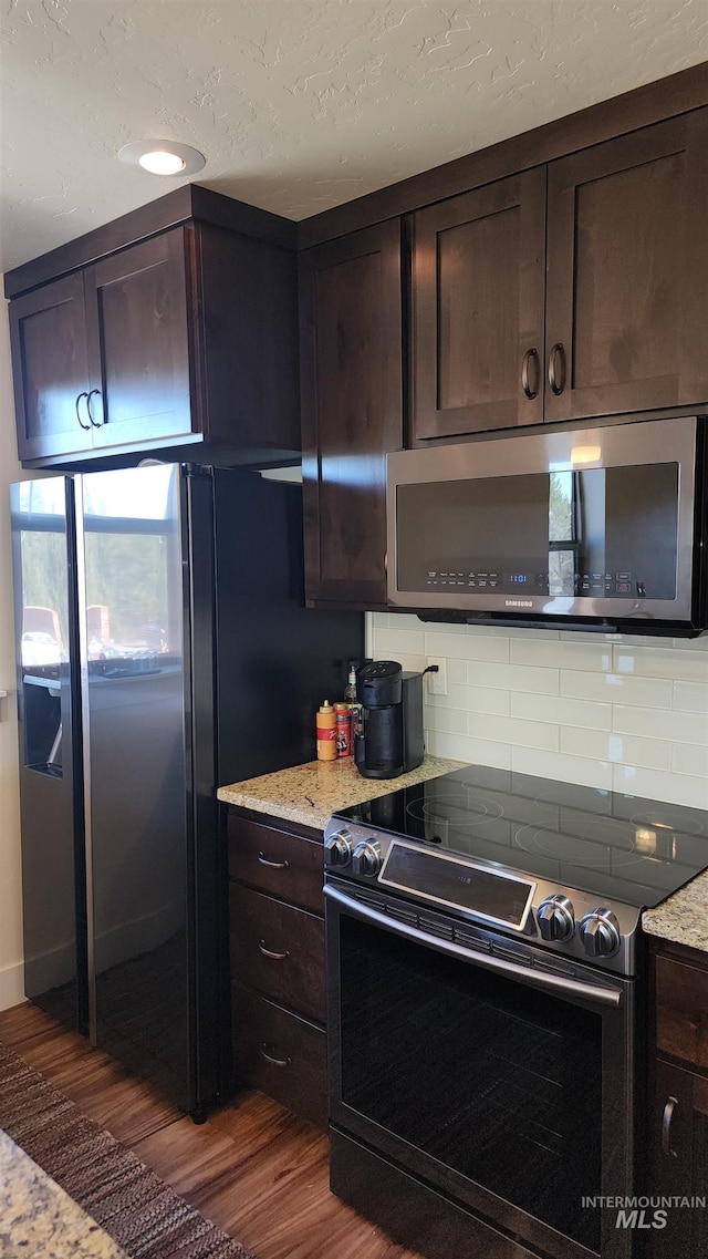 kitchen featuring dark brown cabinetry, dark hardwood / wood-style flooring, black / electric stove, and tasteful backsplash